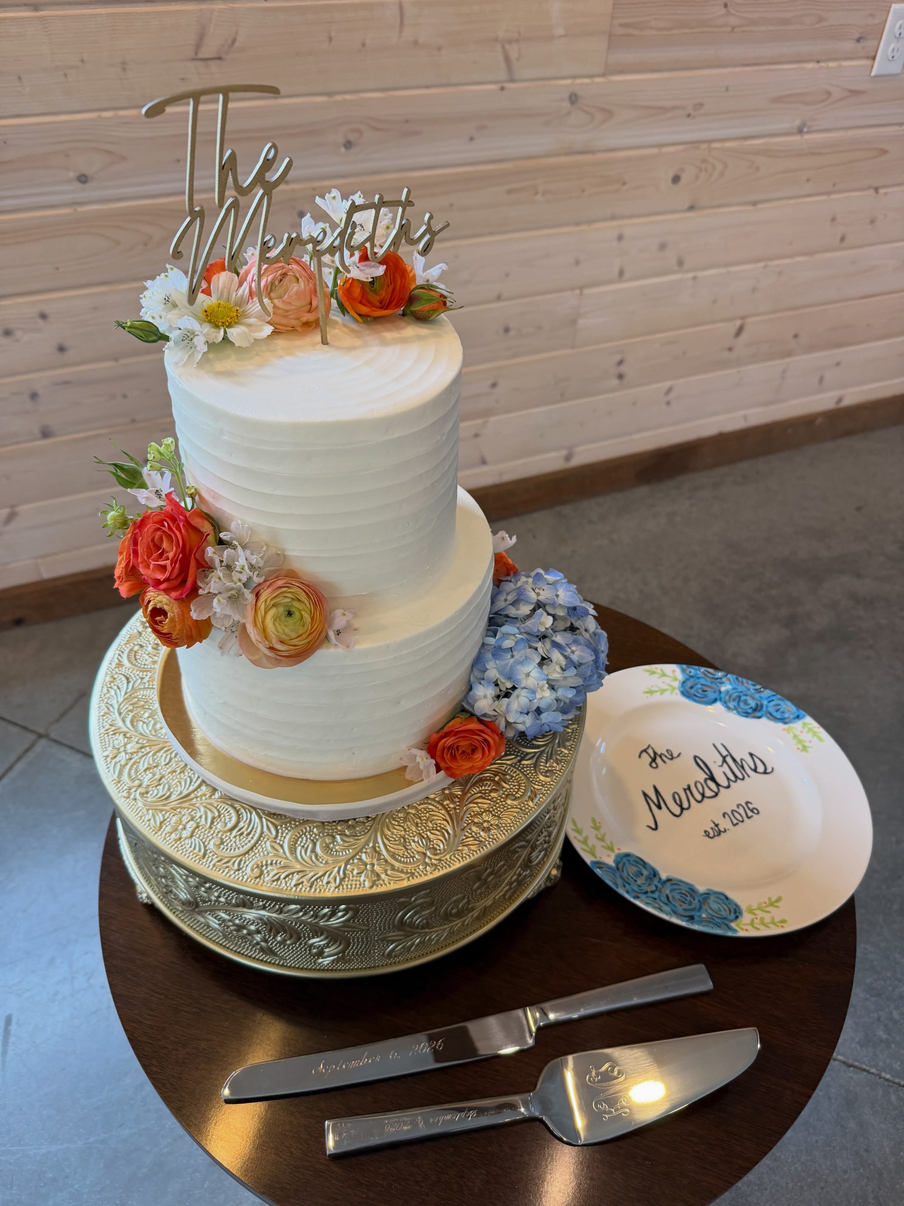 Two-tier wedding cake with fresh flowers and custom topper