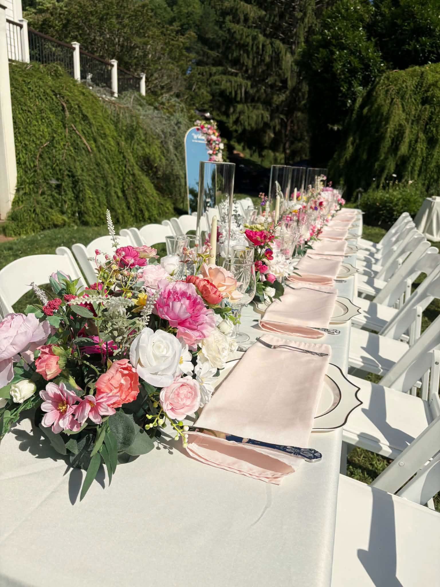 Long outdoor banquet table with pink floral garland runner