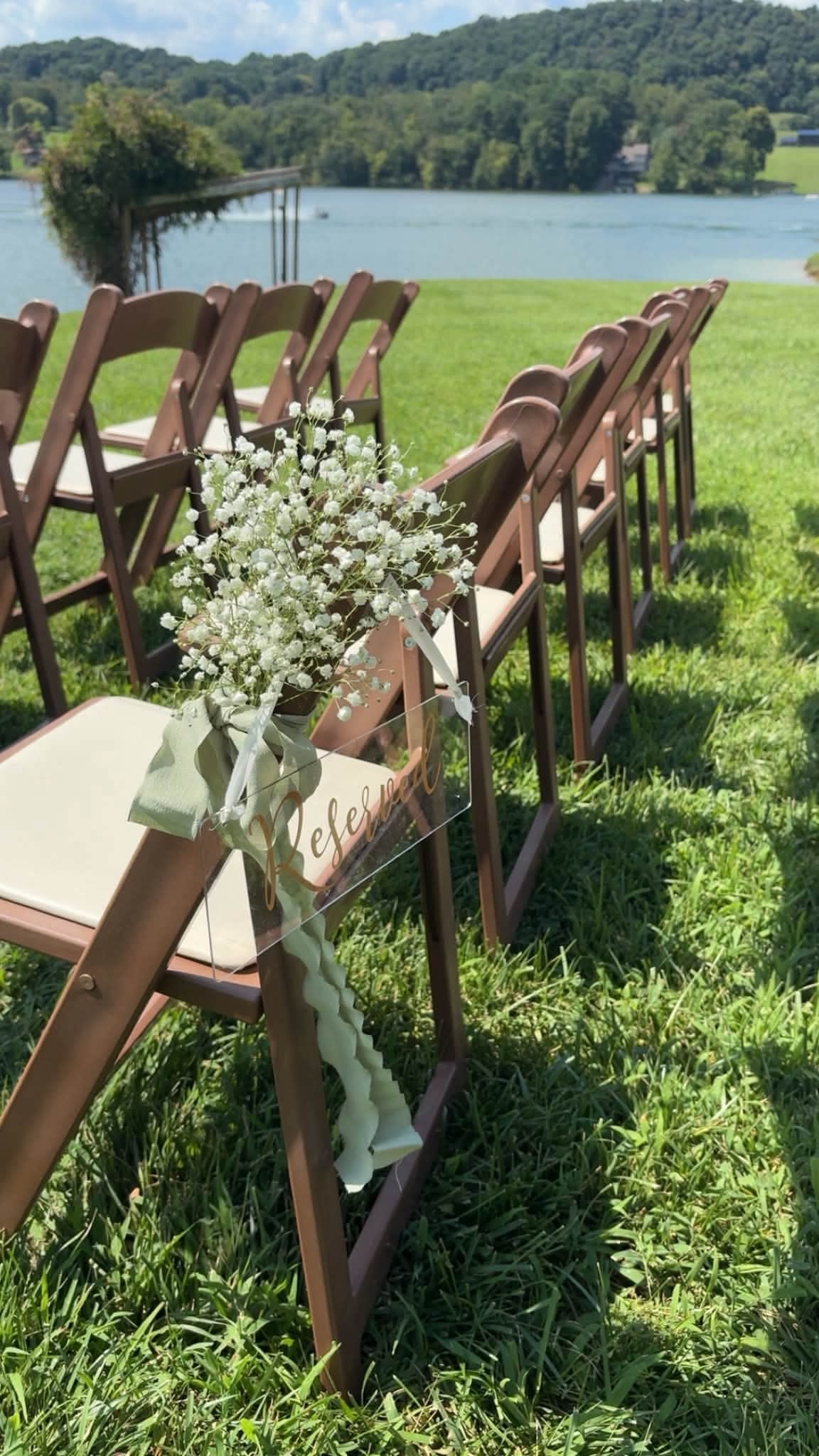Lakeside ceremony chairs with baby's breath and acrylic reserved sign